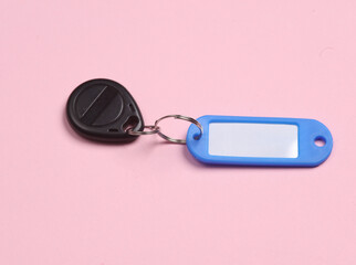 Plastic tag with magnetic key on pink background
