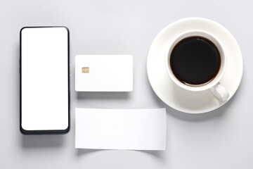 Fototapeta na wymiar Smartphone, White empty bank card with chip, cup of coffee, chack tape on a gray background. Flat lay business concept. Online shopping. Top view