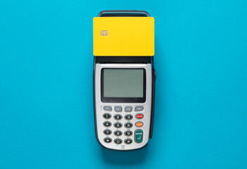 Yellow bank card with chip and pos terminal on a blue background