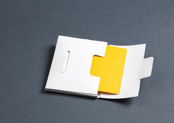 White packing box with yellow bank card on dark gray background. Template for design