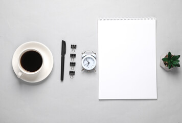 Business layout with sketchbook and coffee cup, alarm clock on gray background. top view