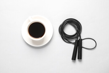 Coffee cup with a skipping rope on a gray background. Energy boost, fitness, healthy lifestyle