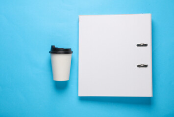 Fototapeta na wymiar Binder folder and coffee cup on blue background. Business concept. Top view