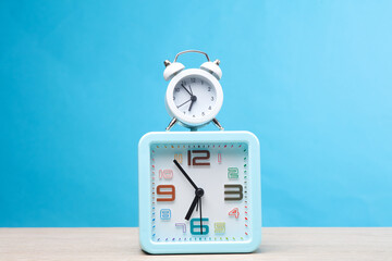 Two alarm clocks (large and small) on a blue background