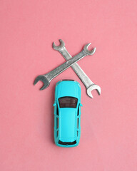 Toy car model with wrench on pink background. Auto service, repair concept. Top view