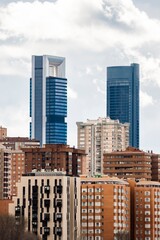 Skyscrapers located in the city of Madrid, Spain, during a cloudy day, rising above the residential buildings. Vertical shot.
