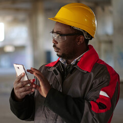 African american workman with smartphone at construction site