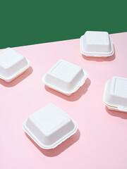 Ecological food delivery packaging. Burger takeaway boxes on green and pink background