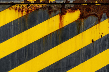 Warning Yellow and Black Diagonal Stripes on Iron Material, Cracked Paint with Visible Rust from Weather or Time