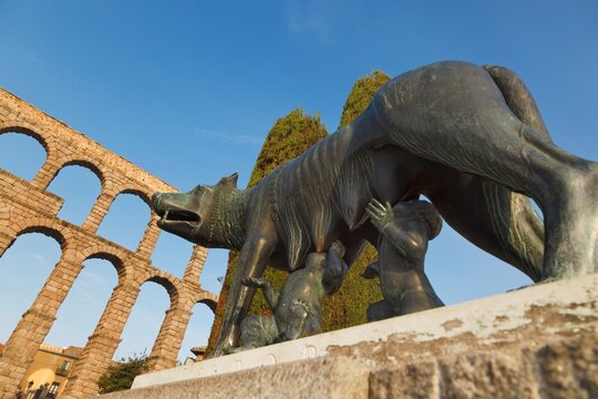Statue Of A She-Wolf Suckling Romulus And Remus With The Roman Aqueduct In The Background; Segovia, Segovia Province, Spain