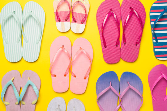 Many bright flip flops on color background, top view
