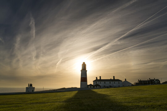 Sunlight Behind A Lighthouse Casts A Shadow On A Grass Field Along The Coast; South Shields, Tyne And Wear, England