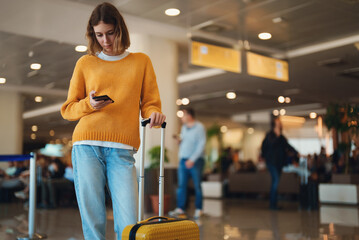 Teenage girl is waiting for her flight at the airport.