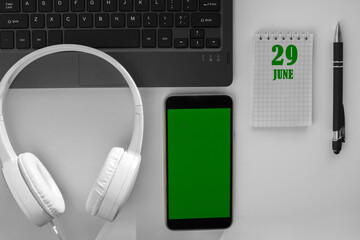 calendar date on a light background of a desktop and a phone with a green screen. June 29 is the...