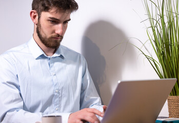 portrait d'un jeune employé de bureau ou homme d'affaires qui travaille devant son ordinateur...