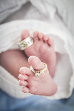 Wedding rings hanging on newborn baby toes; Waco, Texas, United States of America