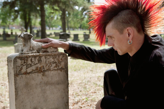 A Young Man Visits A Tombstone In A Cemetery; Edmonton, Alberta, Canada