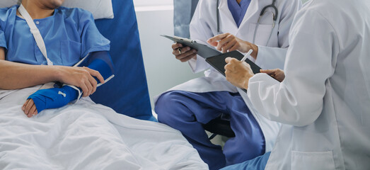 Injured patient showing doctor broken wrist and arm with bandage in hospital office or emergency room. Sprain, stress fracture or repetitive strain injury in hand. Nurse helping customer. First aid.