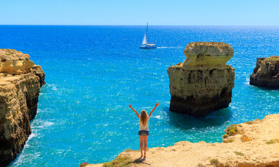 Woman tourist standing with arms raised in Algarve coast- Tourism in Portugal- travel,...