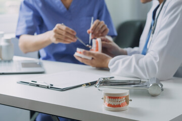 Dentists are discussing dental problems at report x-ray image on laptop screen to patients.