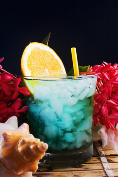 A Tropical Drink Garnished With Flowers And Fruit.