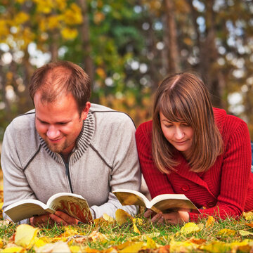 Young married couple reading in a park in autumn; Edmonton alberta canada