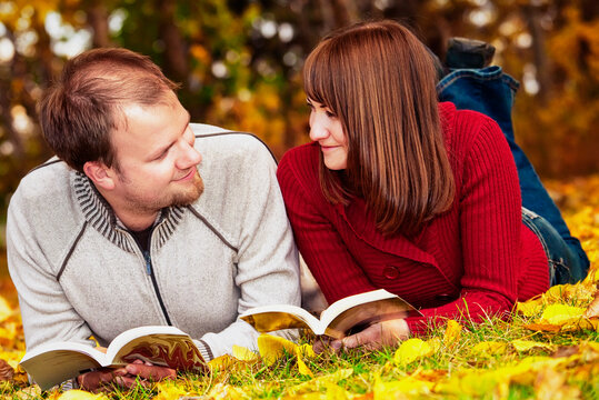 Young married couple reading in a park in autumn; Edmonton alberta canada