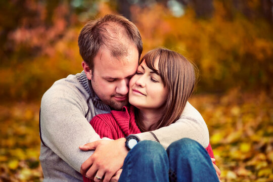 Young married couple embracing intimately in a park in autumn; Edmonton alberta canada