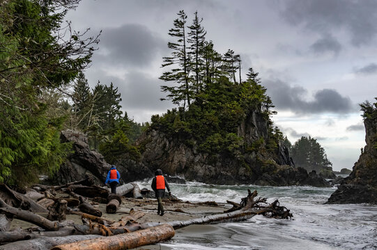 Two people hiking along the rugged coastline at Brady's Beach in Bamfield on Vancouver Island; Bamfield, British Columbia, Canada