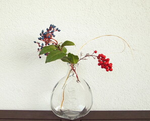 Still life with blue and red berries. Japanese art of flower arrangement. Bouquet of dry branches. Ikebana arrangement.