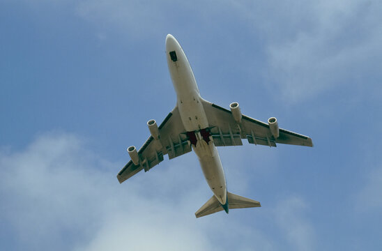 View from directly below of an airplane in a blue sky with cloud, arriving at Ronald W. Reagan National Airport; Washington, District of Columbia, United States of America