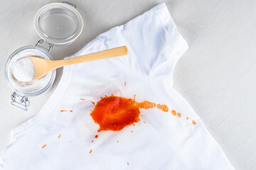 Organic removing sauce stain on clothes with biocarbonat. Spilled ketchup on a white t-shirt. top view. isolated. 