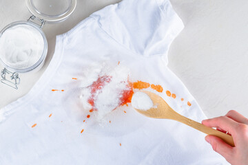 A female's hand removing stain on clothes with baking soda. top view. isolated. The concept...