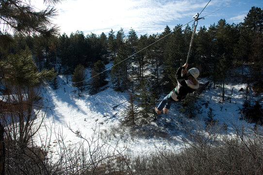 Girl rides a zip-line in winter; Halsey, Nebraska, United States of America