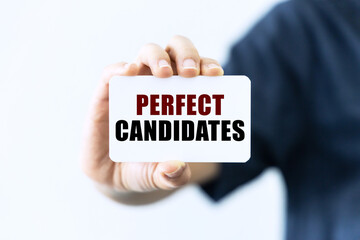 Perfect candidates text on blank business card being held by a woman's hand with blurred background. Business concept about perfect candidates.
