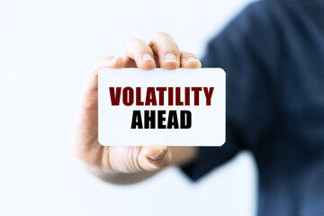 Volatility ahead text on blank business card being held by a woman's hand with blurred background. Business concept about volatility.