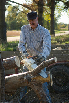 Man saws logs for firewood at a farm near Ashland, Nebraska, USA; Nebraska, United States of America
