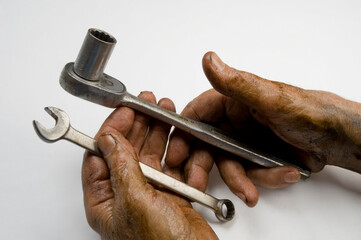 Man with greasy hands holds a tools on a white background; Studio