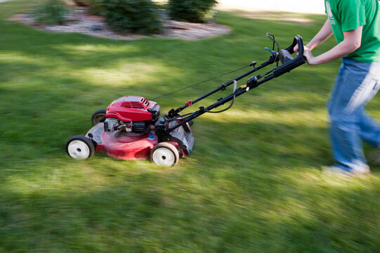 Teenage boy quickly mows a lawn; Elkhorn, Nebraska, United States of America