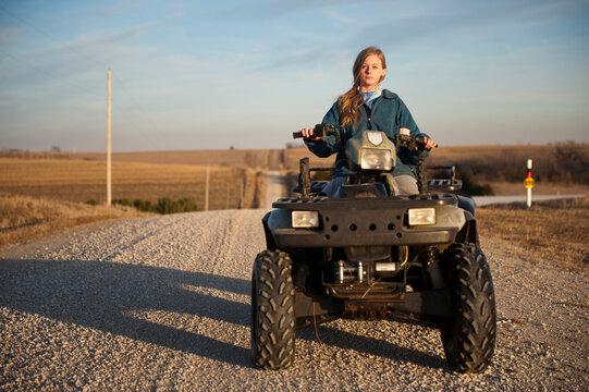 Teenage girl riding a 4-wheeler on a gravel road in the countryside; Dunbar, Nebraska, United States of America