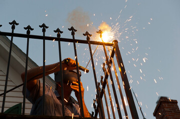 Sparks fly as a man works on a balcony railing using a soldering iron; Dunbar, Nebraska, United States of America
