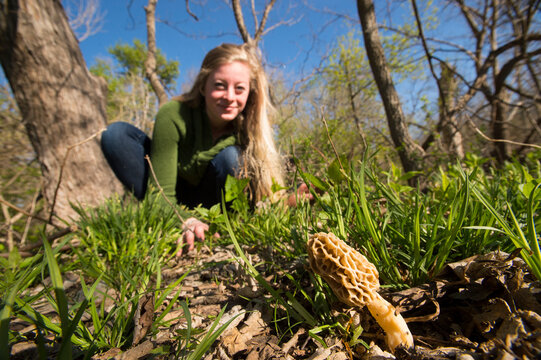 Teenage girl hunts for morel mushrooms in a forest; Nebraska, United States of America