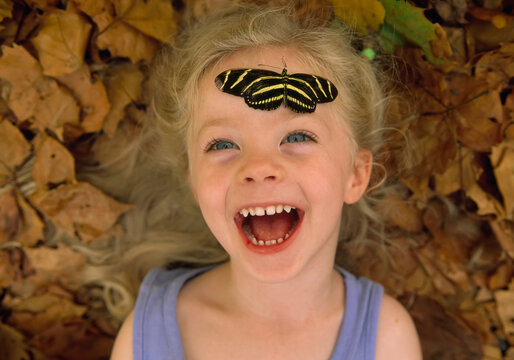 Young girl with zebra butterfly resting on her forehead