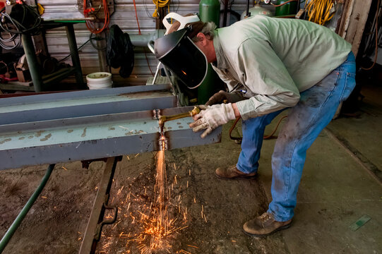 Man uses a cutting torch on a metal beam; Cortland, Nebraska, United States of America