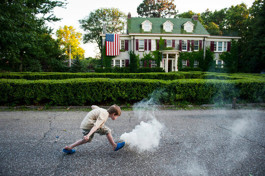 Young boy lights a smoke bomb in a residential street; Lincoln, Nebraska, United States of America