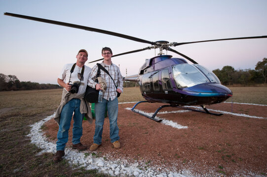 Male photographer and his son arrive by helicopter at Chitengo Camp inside Gorongosa National Park, Mozambique; Gorongosa National Park, Mozambique