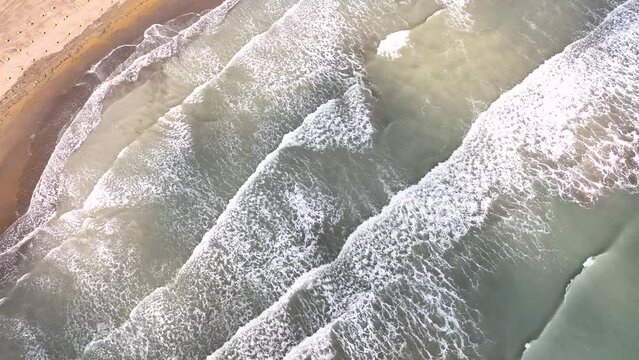 LIGNANO, ITALY - APRIL, 2023: Lignano beach coastline at Adriatic sea in Italy, Europe during summer at windy cloudy day. Big waves on the sea water.