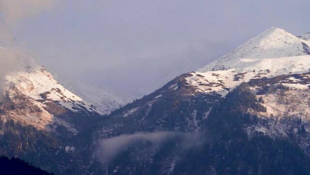 panning shot of snow covered himalaya mountains with clouds on them at sunset sunrise near atal tunnel manali kullu showing serene beauty of himachal pradesh India