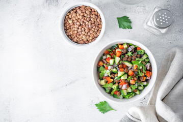 Green lentil red bell pepper cucumber parsley salad in a bowl