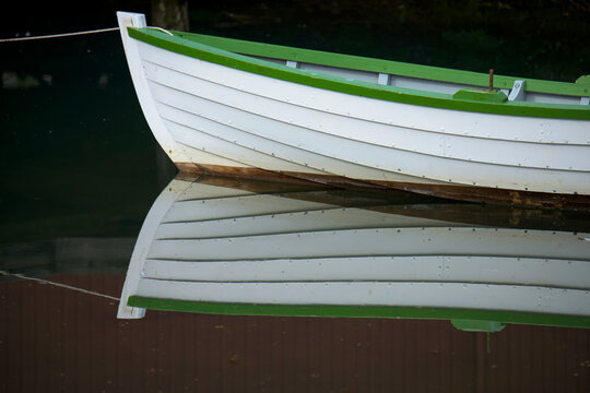 Boat moored at the Siglufjordur Herring Museum in Iceland, it's mirror image reflected in the tranquil water; Iceland